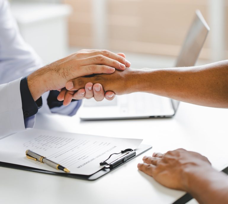 Doctor holding a patient's hand during a consultation